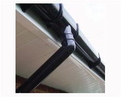 Close-up view of newly installed black uPVC guttering, downpipe, and brackets fitted against white uPVC soffits.