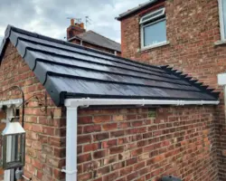 Newly tiled pitched roof on a brick home extension featuring dark interlocking tiles and white uPVC guttering.