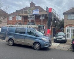 FJ Roofing branded work van parked in front of a residential house undergoing roof replacement with scaffolding