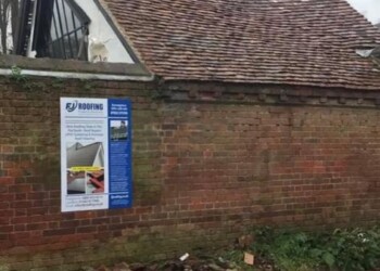 Professional roofer repairing damaged clay roof tiles on a traditional pitched residential roof.