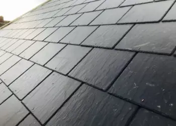 Angled view of a newly installed dark pitched slate roof showing textured individual tiles and clean lines.