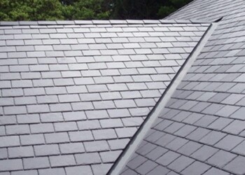 Professional installation of grey slate roof tiles showing clean valleys and tight alignment.