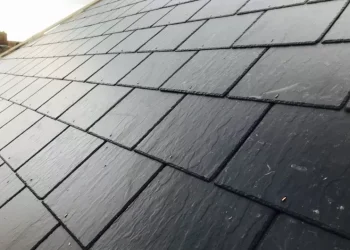 Angled view of a newly installed dark pitched slate roof showing textured individual tiles and clean lines.